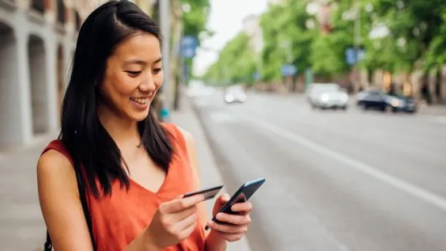 A woman holding her card and phone